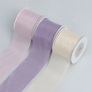 Close-up of translucent organza ribbon rolls in pink, purple and cream for DIY crafts