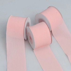 Detailed view of three rolls of pink pleated chiffon ribbons for gift wrapping and DIY crafts