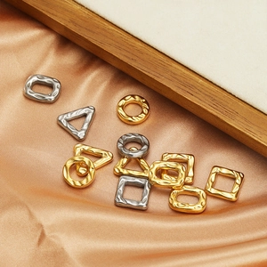 Textured geometric metal charms with gold and silver finishes on silk fabric background
