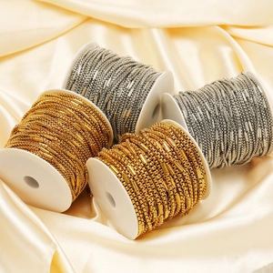 Golden and silver stainless steel bead chain rolls on champagne satin background