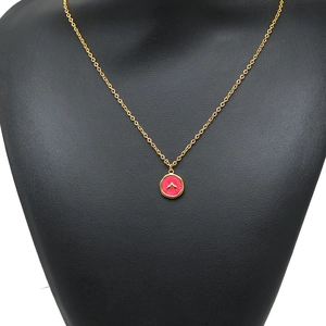 Pendentif queue de sirène dorée avec insert rose sur porte-bijoux noir élégant