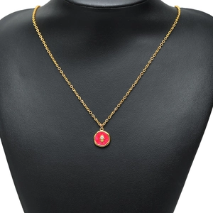 Gold chain necklace with red enamel evil eye pendant displayed on a black jewelry bust