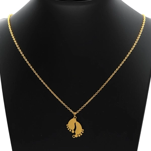 Collar con colgante de pies de bebé en acero inoxidable dorado sobre soporte negro