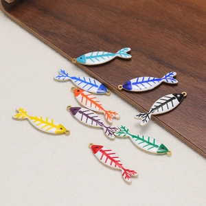 Colorful fishbone enamel pendants in various colors on a wooden tray for DIY jewelry