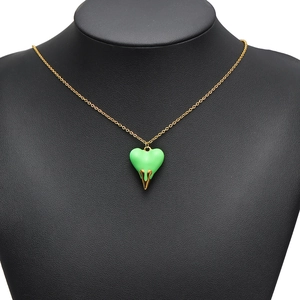 Polished gold necklace with a vibrant green heart-shaped pendant on a black bust
