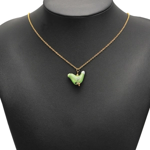 Delicate gold chain necklace with a vibrant green ceramic bird pendant on a black bust display