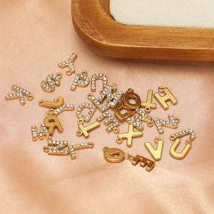 Polished gold stainless steel alphabet pendants with rhinestones on satin fabric