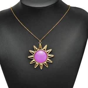 Goldene Halskette mit Sonnenstrahl-Anhänger und violettem Cabochon auf schwarzer Büste