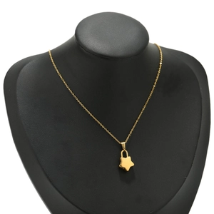 Detalle de un colgante de candado con forma de estrella dorada en una fina cadena sobre busto