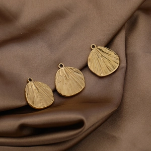 Macro detail of leaf-shaped gold stainless steel pendants with embossed texture