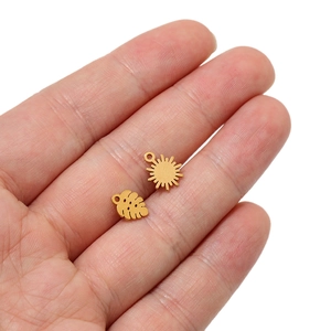 Détail des pendentifs en acier inoxydable doré mat motif tournesol et feuille de monstera