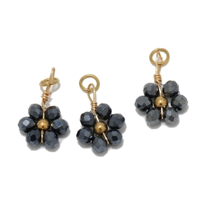 Close-up of three handmade crystal flower charms with dark grey faceted beads and gold loop
