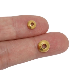 Dettaglio di due perline distanziatrici in acciaio placcato oro 18K mostrate sulla mano