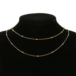 Detail van 18k vergulde slangenketting met gepolijste kralen op een zwarte halsmodel