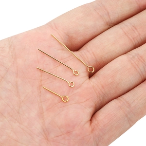 Macro detail of four gold plated stainless steel eye pins in different lengths on a palm