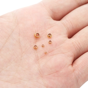 Vista macro de cuentas de crimpado de acero dorado para joyería en la punta de los dedos
