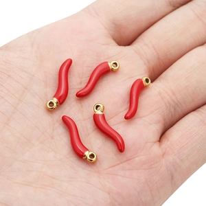 Set van vijf rode emaille chili peper hangers met gouden ringen getoond in de hand