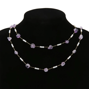 Dettaglio collana in acciaio inossidabile dorato con cristalli viola naturali e perle bianche