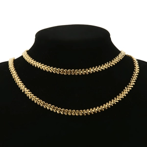 Détail du collier plaqué or 18k avec motif d'épis de blé sur un présentoir noir