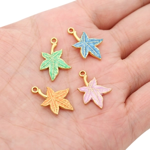 Maple leaf enamel pendants in four colors held in hand for jewelry DIY accessories