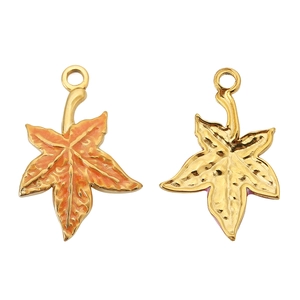 Macro detail of maple leaf pendants with orange enamel finish and golden metal texture