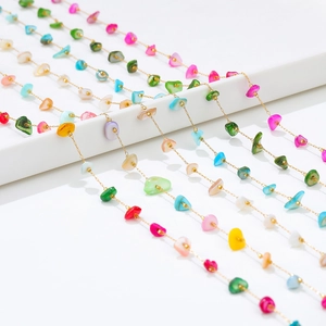 Detail of 18k gold plated chains with colorful irregular shell charms in boho style