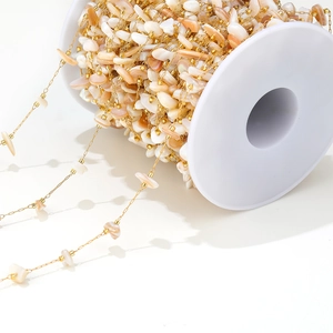 Macro detail of natural shell beads on gold plated DIY jewelry chain wound on a spool