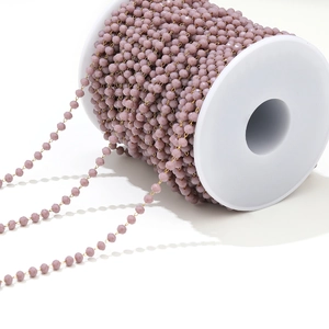 Detail of lavender crystal beads on gold wire, wound on a white spool for DIY jewelry