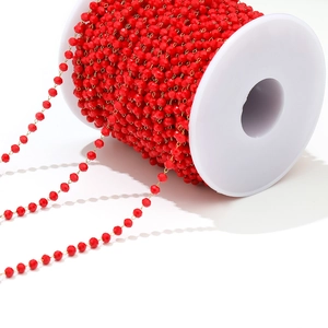 Macro shot of red faceted crystal beads on golden chain roll for DIY jewelry making