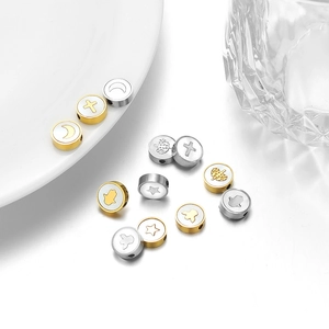 Makro-Detail von Edelstahl-Anhängern in Gold und Silber mit Himmelsymbolen für DIY-Schmuck
