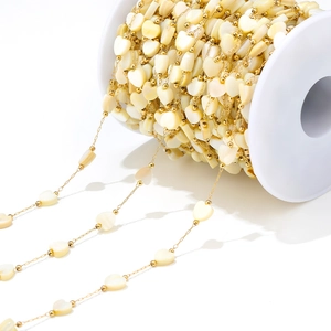 Close-up of 6mm golden bead chain with cream heart shell charms for DIY jewelry making