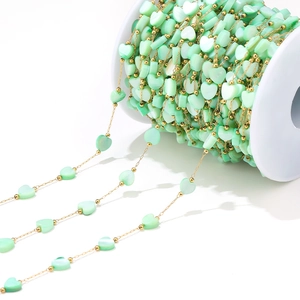 Detail view of 6mm mint green heart shell beads on a gold chain for DIY jewelry