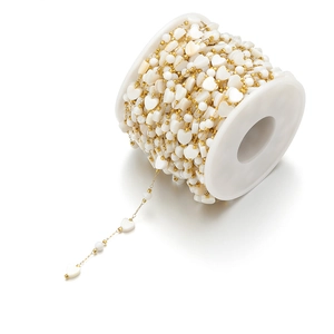 Detail of 8mm white heart shell beads and gold chain on spool for DIY jewelry