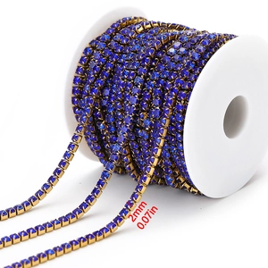 Detail of 2mm dark blue rhinestone chain with gold claw base on a white spool roll