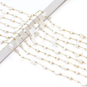 Macro detail of golden chain with shell star, heart, and flower charms for DIY jewelry