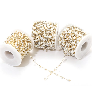 Macro view of gold-plated chains with white shell star and round beads on white spools