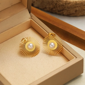 Detail of golden sunflower pearl earrings on a velvet jewelry box with stone background