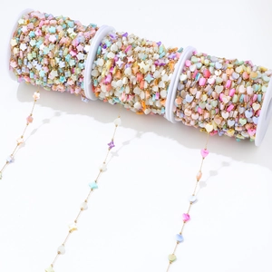 Macro detail of colorful heart and star charms on a 1mm gold DIY necklace chain roll