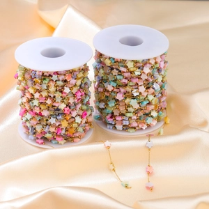 Macro shot of colorful star-shaped beads on a golden stainless steel chain for DIY jewelry