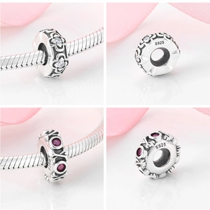 Close-up of S925 sterling silver charms with floral patterns and red zircon stones