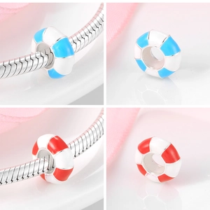 Macro detail of red and blue enamel lifebuoy charms on a silver snake chain bracelet