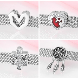 Macro detail of S925 sterling silver charms featuring heart and dreamcatcher designs