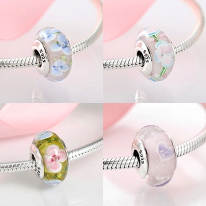 Macro detail of S925 sterling silver charms with floral glass and heart patterns