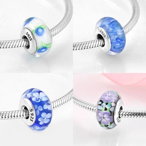 Macro shot of S925 sterling silver glass charms with floral patterns for DIY bracelets