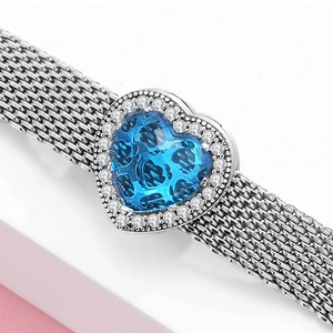 Dettaglio del bracciale a maglia d'argento con pendente a cuore e zirconi blu e bianchi