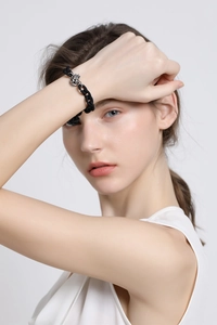 Detail of punk style matte black chain bracelet with a vintage silver skull crown charm
