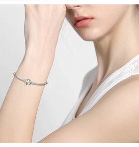 Detailed view of a silver snake chain bracelet with a blue sun and moon charm on a wrist