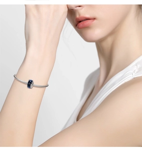 Close-up of a snake chain bracelet with deep blue faceted glass charm on a wrist