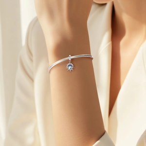 S925 zilveren armband met maansteen sterhanger aan de pols van een vrouw met warme achtergrond