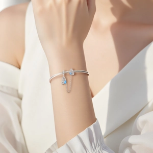 Silver butterfly bracelet with blue zircon stone and snake chain on model's wrist